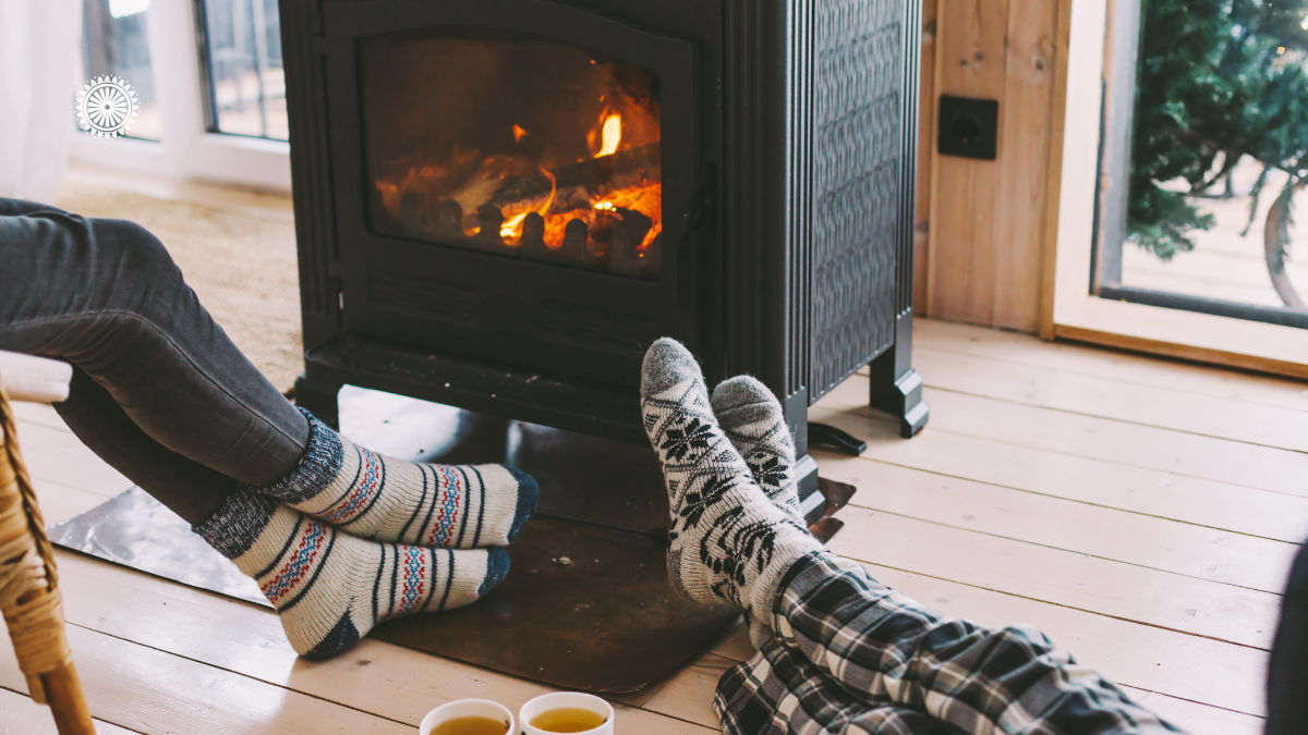 Couple sitting by a fire toasting their toes in winter.